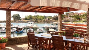 An outdoor dining area with stone pillars, wooden chairs, and tables. - Vacation home Delfar by Interhome (Lošinj / Veli Lošinj)