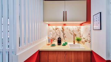 Une cuisine moderne avec un dosseret en marbre, des armoires en bois et un mur d’accent rouge.