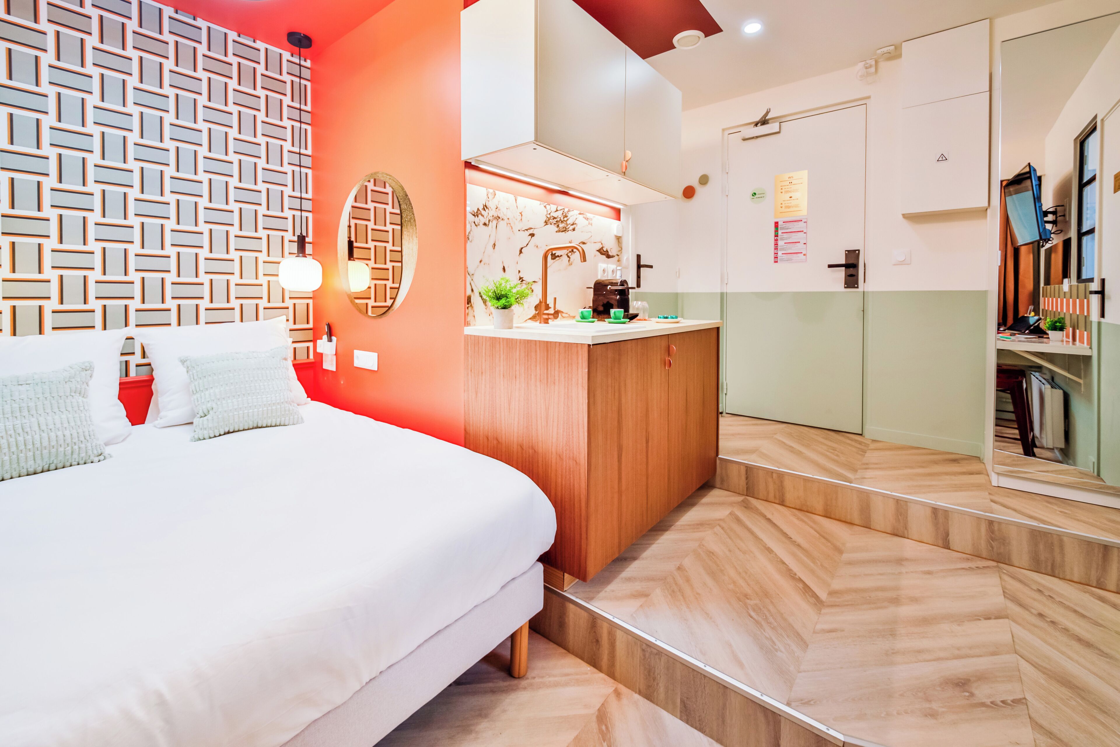Une chambre d’hôtel moderne avec un grand lit, un bureau en bois et une kitchenette.
