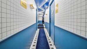 A hallway with tiled walls, a blue carpet, and directional signs. - WS Molitor - Auteuil (Paris)