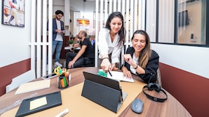 A modern office space with a round table, laptops, and people working. - WS Molitor - Auteuil (Paris)