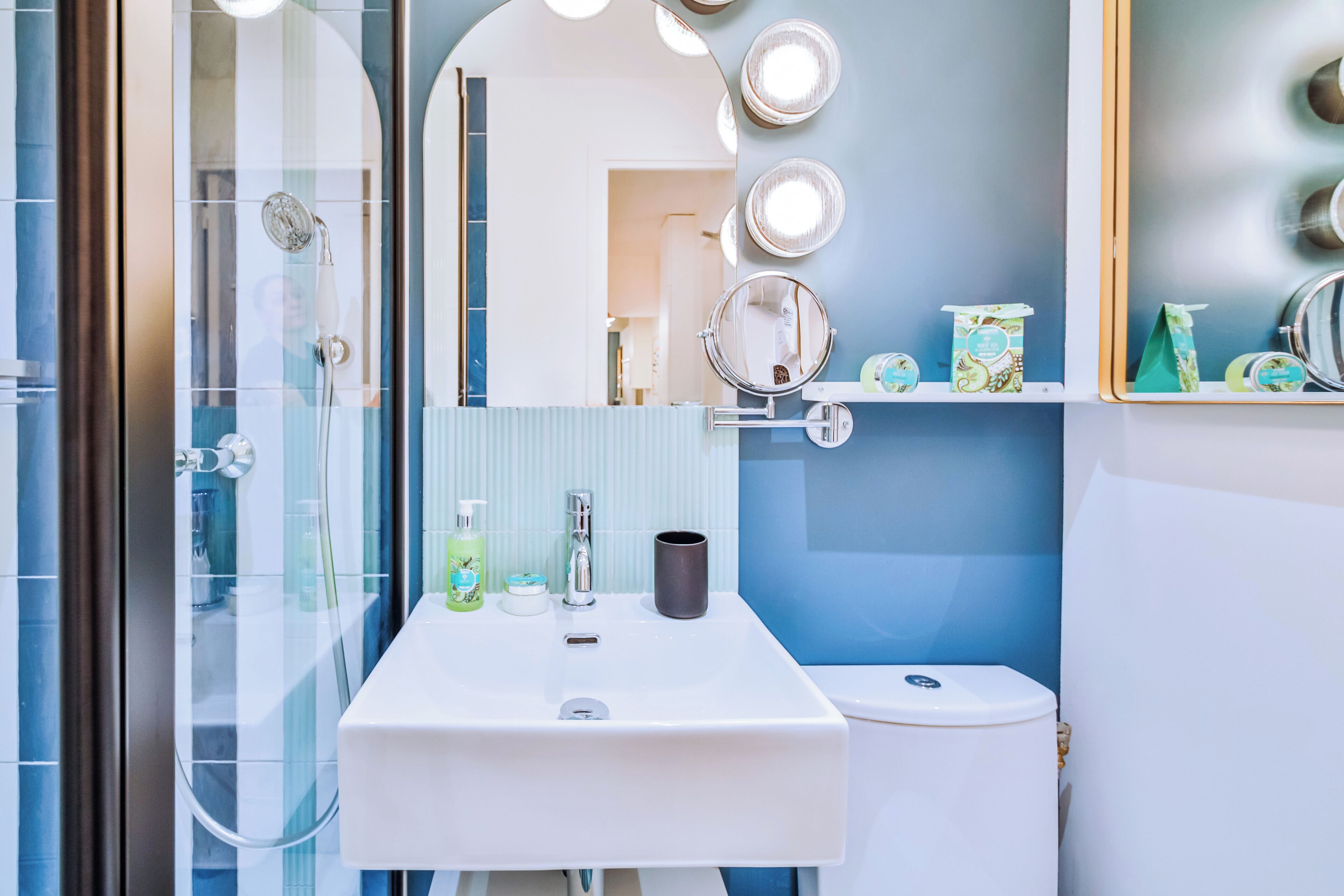 A bathroom with a glass shower enclosure, a white sink, and a toilet.