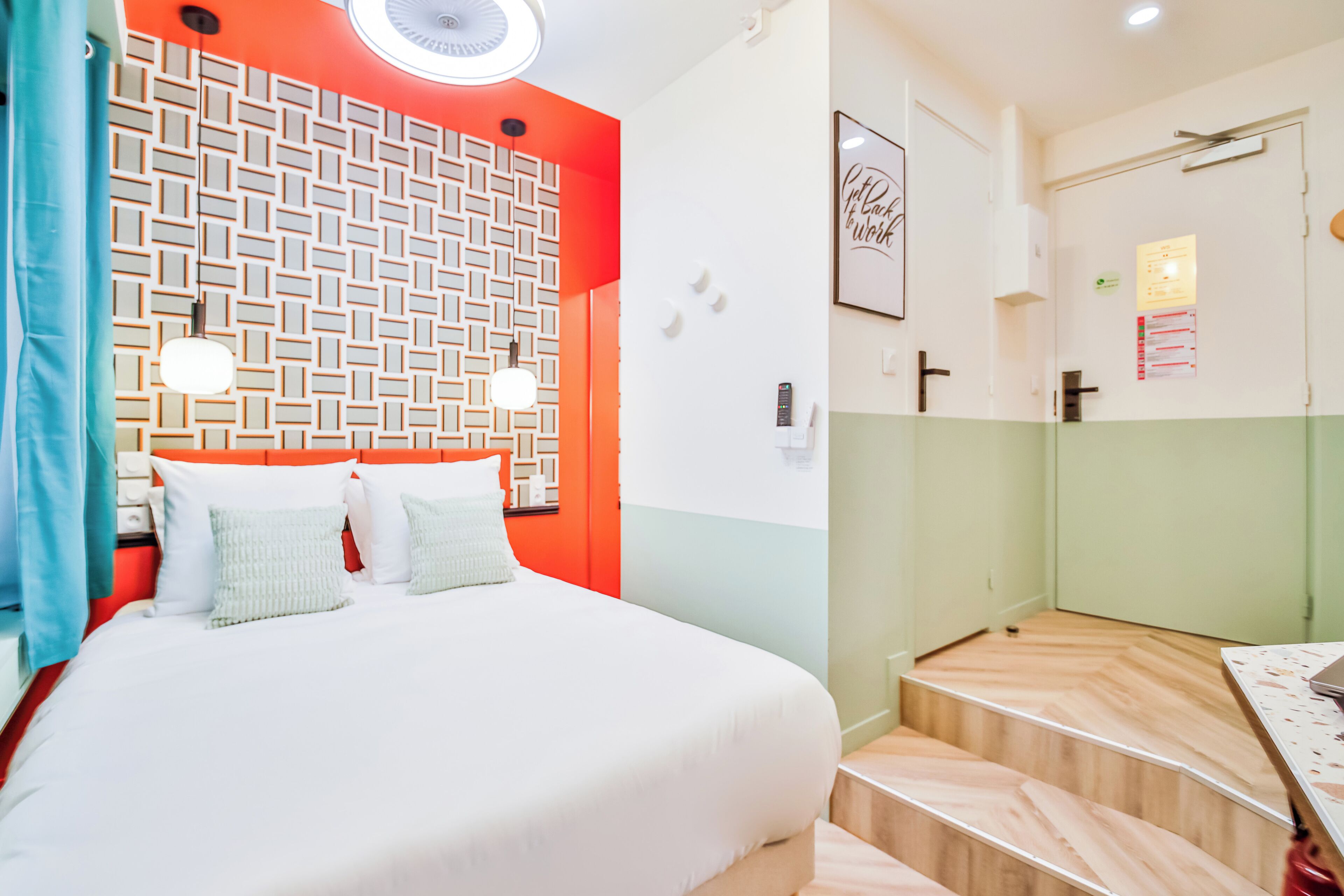 A hotel room with a bed, a mirror, a desk, and a bathroom.