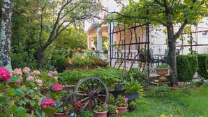 Un jardin agrémenté d’une brouette ancienne, de plantes en pot et d’un belvédère.