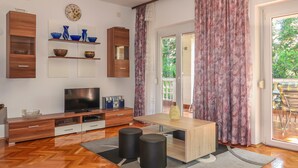 Un salon moderne avec un téléviseur, des meubles en bois et une grande fenêtre avec des rideaux.