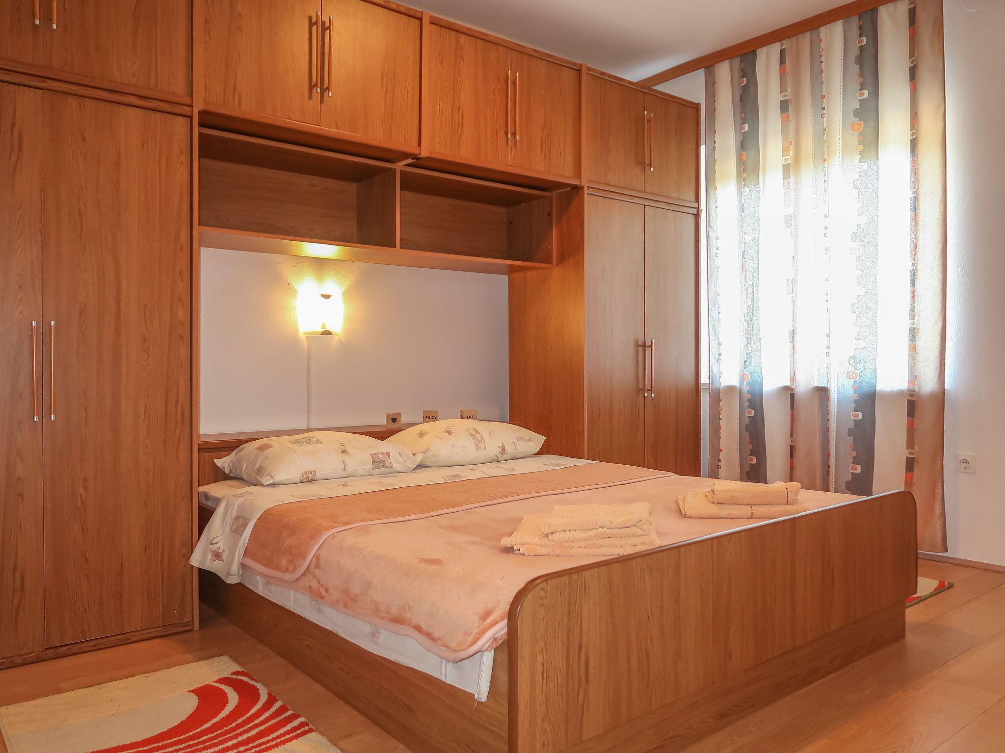 A bedroom with a wooden bed, built-in wardrobe, and a bedside lamp.