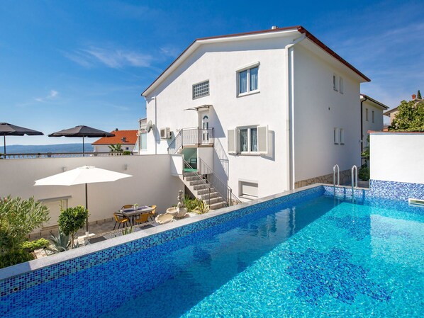 A two-story white building with a swimming pool.