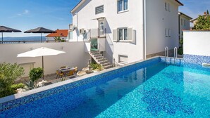 Ein weißes, zweistöckiges Gebäude mit Swimmingpool.