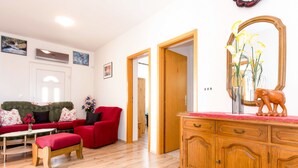 Ein Wohnzimmer mit einem grünen Sofa, einem roten Sessel und einer Holzkombination mit Spiegel.
