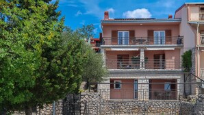 Un edificio residencial de varios pisos con balcones y un muro de piedra.