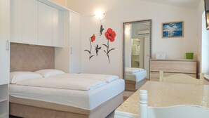 A bedroom with a bed, a nightstand, a mirror, and a bathroom visible through an open door. - Apartment Marija by Interhome (Krk/Baška)