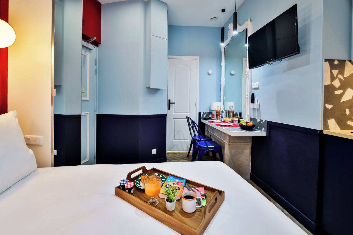 Habitación de hotel con cama, bandeja de desayuno, televisión y escritorio con silla.