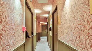 A hallway with patterned wallpaper, doors, and a carpeted floor. - WS Louvre - Saint-Roch (Paris)