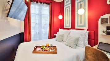 Een hotelkamer met een bed, een ontbijtkarretje en een aan de muur bevestigde televisie.