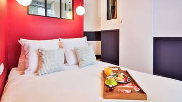 A hotel room with a bed, a tray with breakfast items, and a red wall.