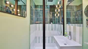 Une salle de bain moderne avec un grand miroir, un lavabo blanc et un espace douche.
