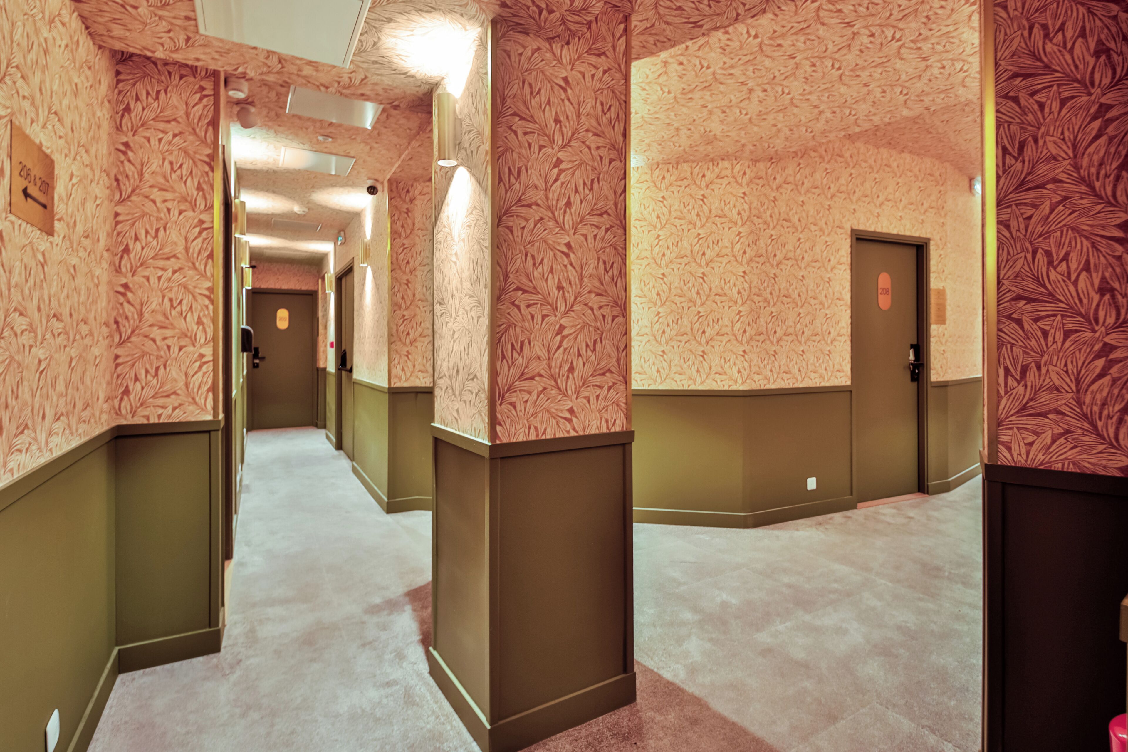 Ein Hotelkorridor mit ornamentalem Wandpapier, Teppichböden und Türen zu Zimmern.