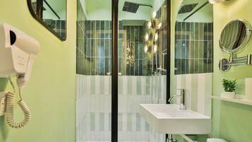 A bathroom with a glass-enclosed shower, a white sink, and a hairdryer mounted on the wall.