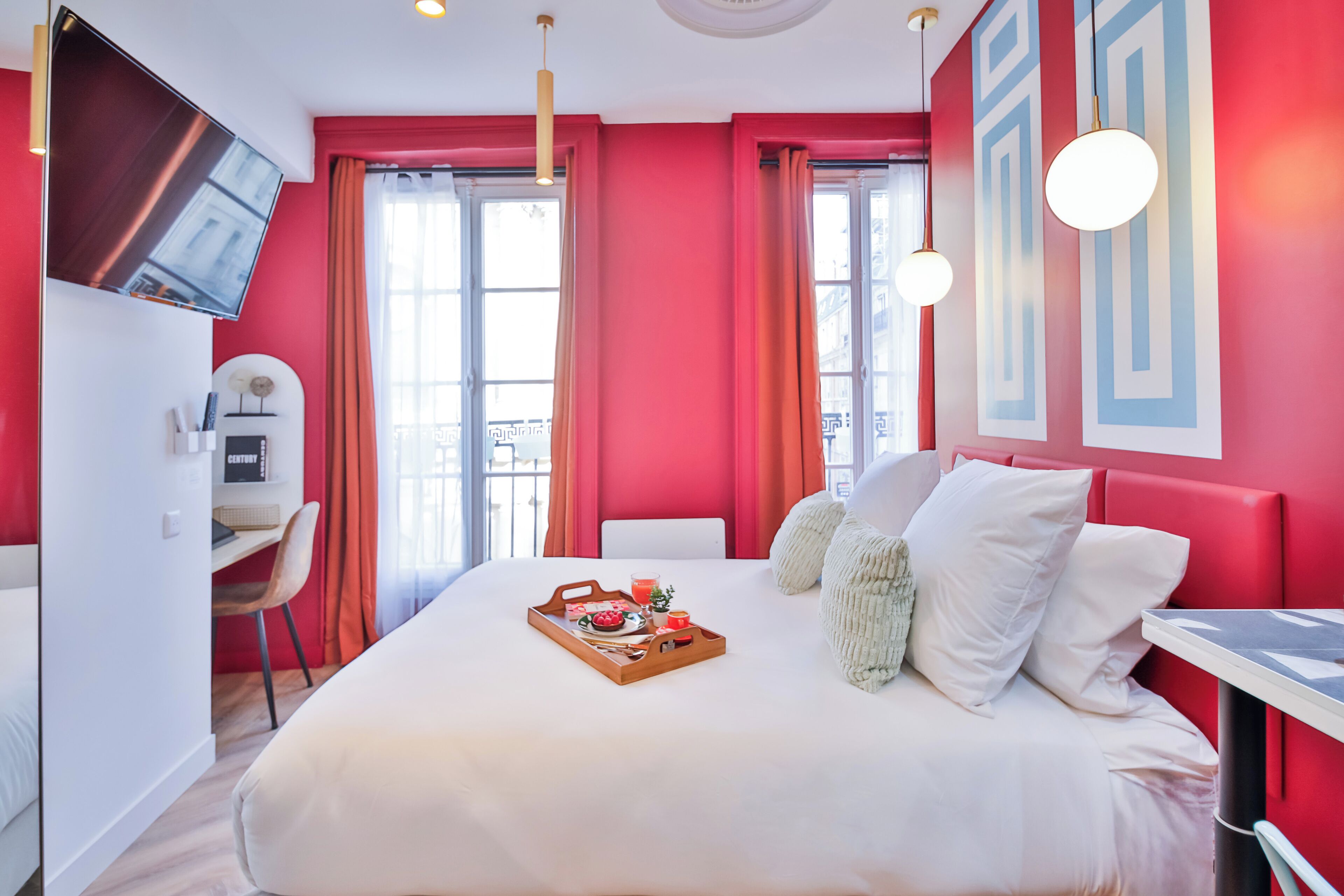 Una habitación de hotel moderna con una cama grande, un escritorio y un televisor montado en la pared.