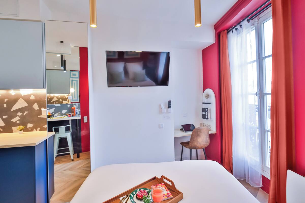Una habitación de hotel moderna con cama, escritorio, televisor y zona de comedor.