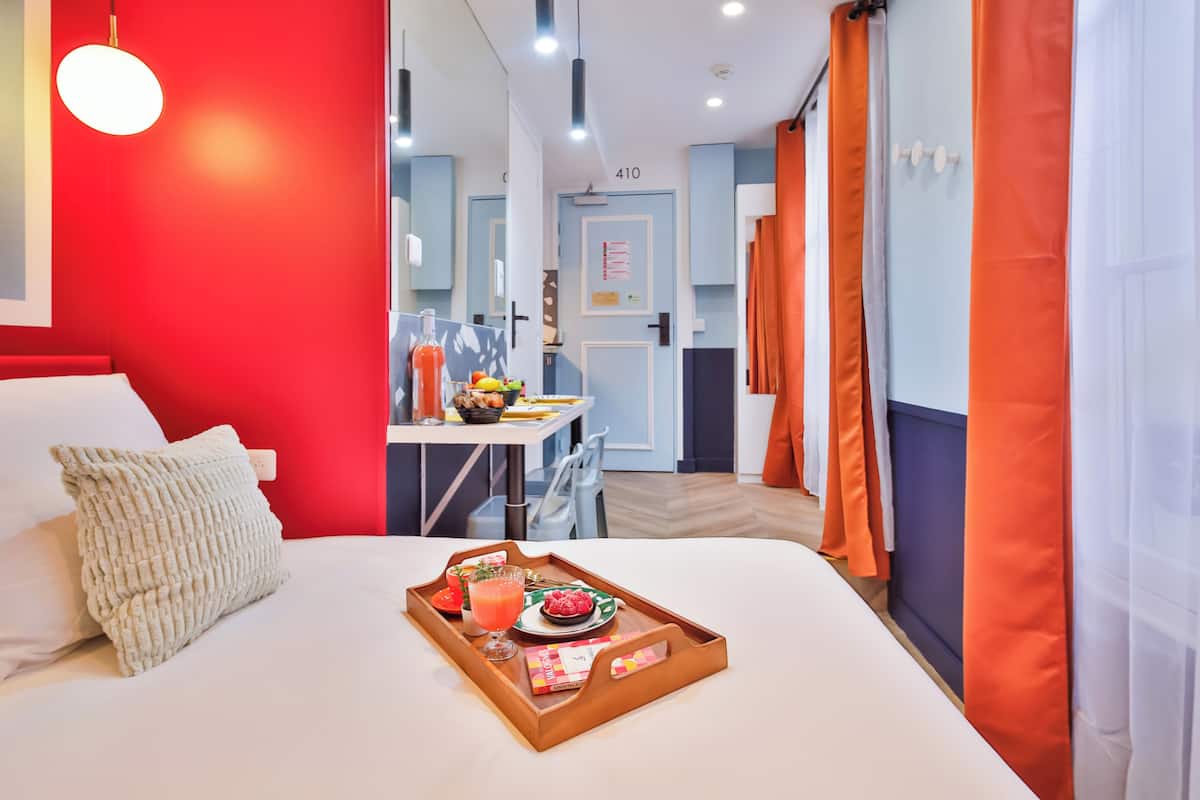 Una habitación de hotel con cama, bandeja de desayuno y vista al comedor.