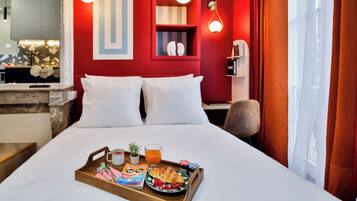 Une chambre d’hôtel avec un lit, un plateau de petit-déjeuner et un mur rouge agrémenté d’une étagère.