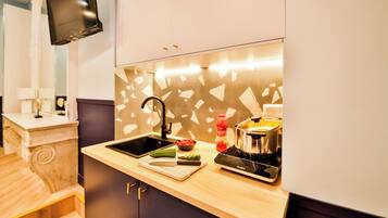 Une cuisine moderne équipée d’une cuisinière intégrée, d’un évier et d’un téléviseur à écran plat fixé au mur.