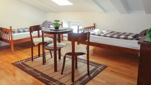 Ein gemütliches Schlafzimmer im Loft-Stil mit Dachfenster, einem Esstisch mit Stühlen und einem Bett mit karierter Decke.