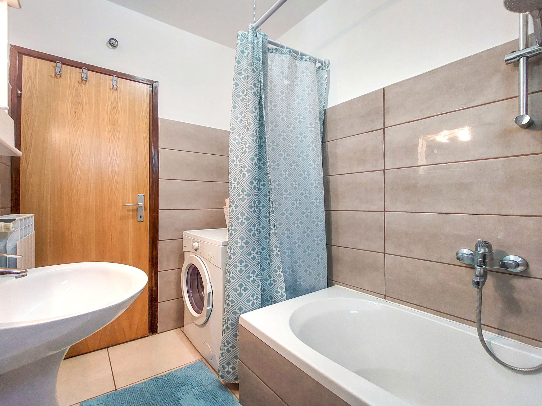 A bathroom with a sink, washing machine, and bathtub.