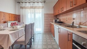 A kitchen with wooden cabinets, a sink, and a dining area with a table set for two.