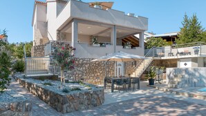 A modern two-story house with a stone facade, a covered patio with outdoor furniture, and a staircase leading to a balcony. - Lavendel by Interhome (Krk/Malinska)