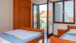 Ein Schlafzimmer mit zwei Betten, einem Holzschrank und einem Balkon mit ornamentverzierten Glastüren.