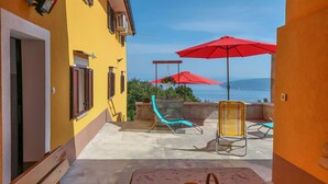 Ein Balkon mit Tisch, Stühlen und einer Fruchtkorb.
