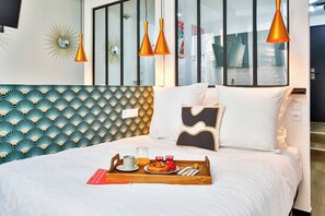 A neatly made bed with a tray of breakfast items, a modern headboard, and a large window with a view of the city. - WS Hôtel de Ville - Beaubourg (Paris)