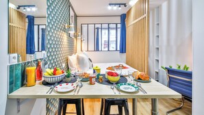 A dining area with a table set for two, featuring a variety of fruits, pastries, and beverages. - WS Hôtel de Ville - Beaubourg (Paris)
