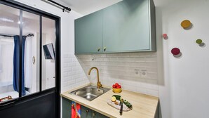 A compact kitchen with a sink, a cutting board with vegetables, and a small bowl of tomatoes. - WS Hôtel de Ville - Beaubourg (Paris)