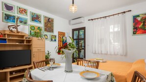 Un coin repas avec une table dressée pour deux personnes, un téléviseur et diverses œuvres d’art accrochées aux murs.