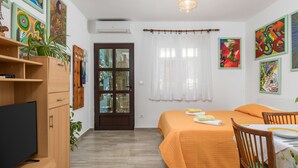 Une chambre à coucher moderne, avec un lit, une télévision, une table à manger et des œuvres d’art accrochées aux murs.