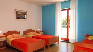 Une chambre d’hôtel avec deux lits simples, une petite table, une table de chevet, un tableau au mur et une fenêtre avec des rideaux.