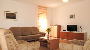 Un salon comprenant un canapé, une table basse, un téléviseur et un meuble.