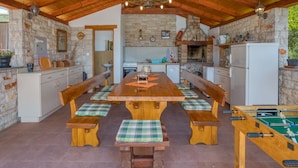 Una cocina rústica con pared de piedra, vigas de madera y una mesa de madera con bancos.