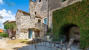 A stone building with a covered outdoor seating area featuring a table and chairs. - Rotonda by Interhome (Labin)