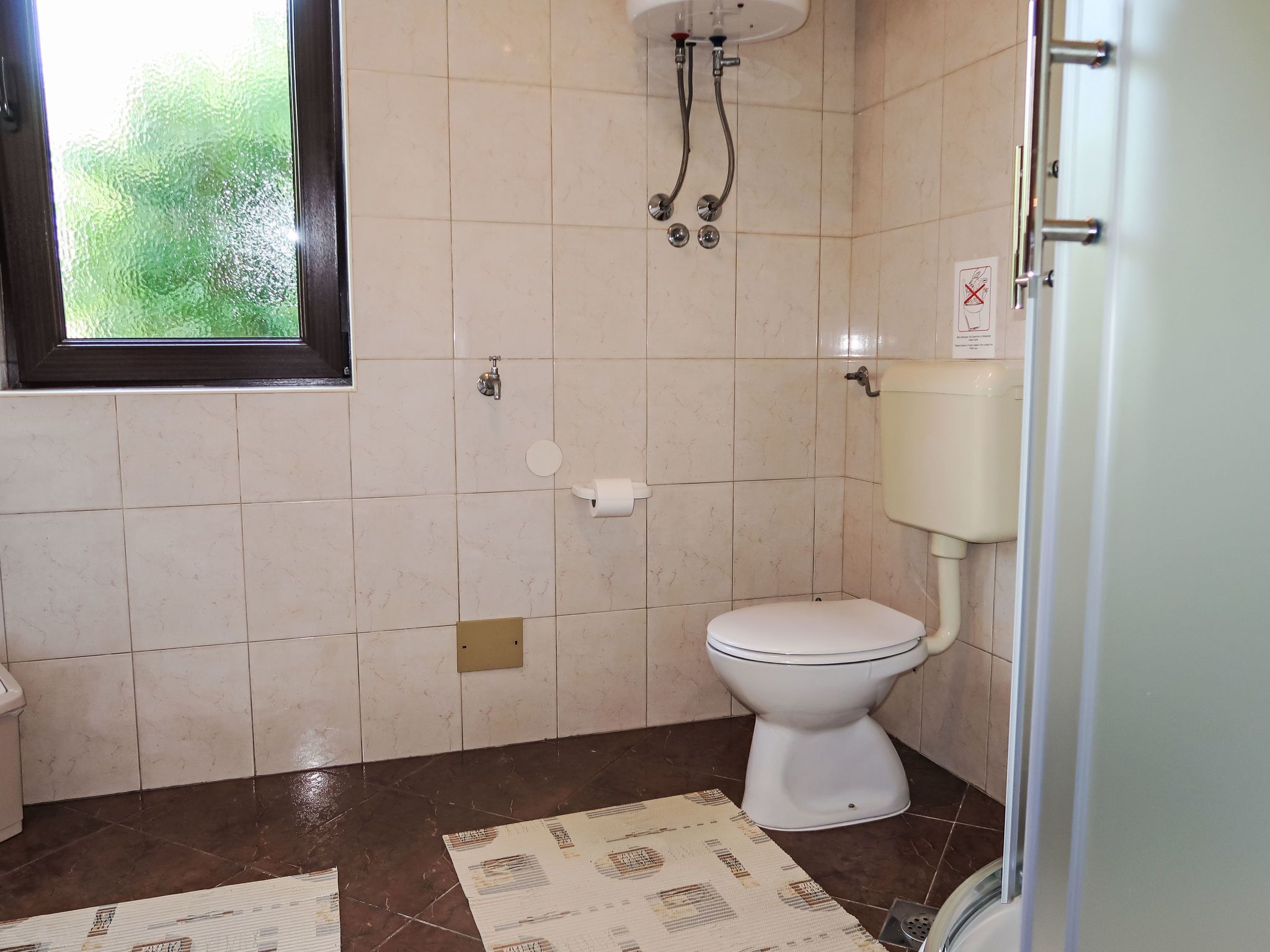 A bathroom with a toilet, a shower, and a window.