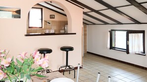 A dining area with a table set for two, a vase with flowers, and a view of the kitchen through an archway. - Violetta by Interhome (Labin)