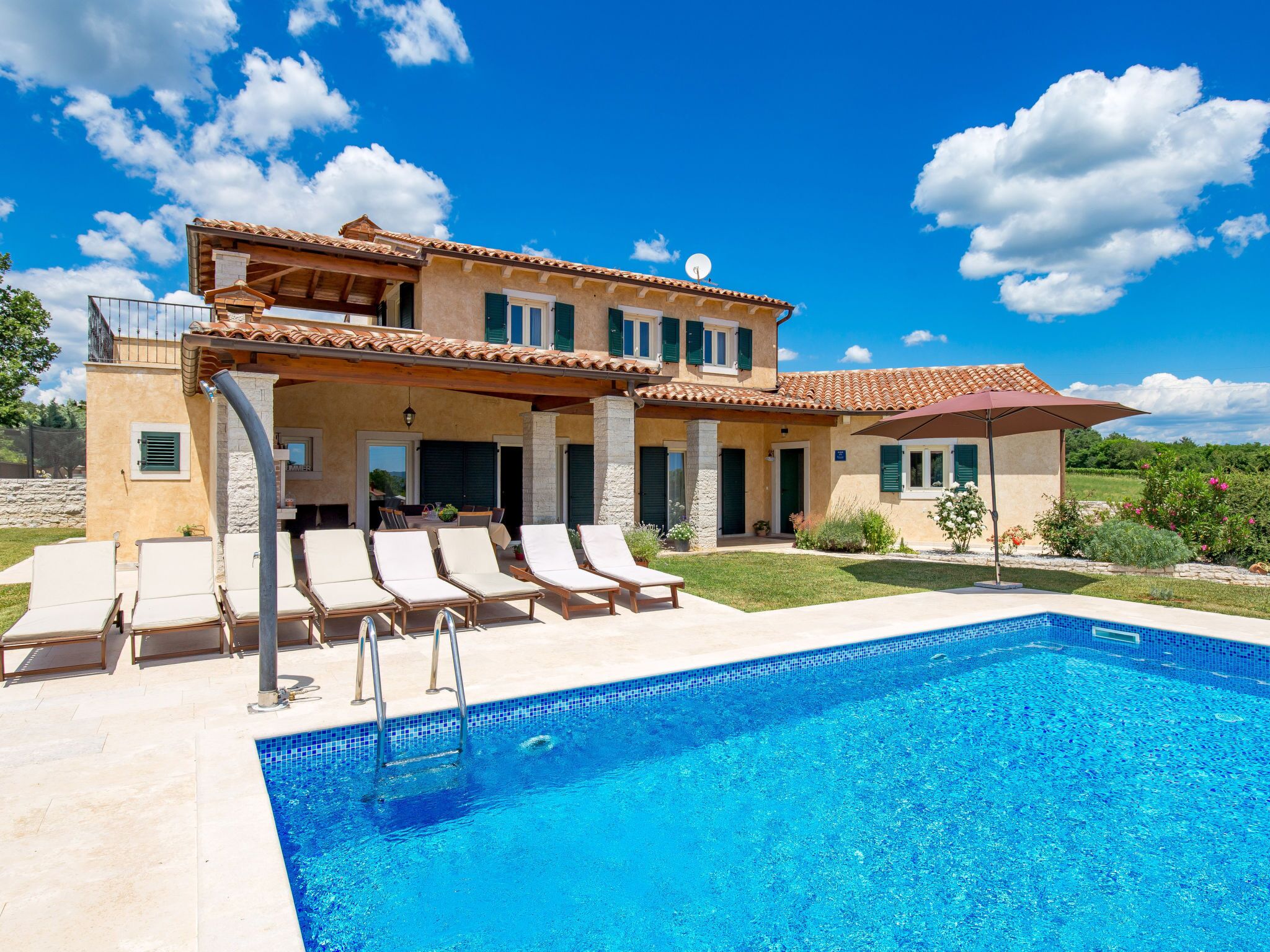A two-story house with a swimming pool, outdoor seating, and a garden.