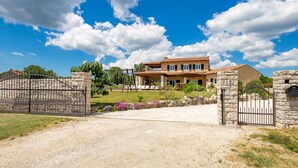 A two-story house with a gravel driveway and a metal gate. - Baretuni by Interhome (Labin)