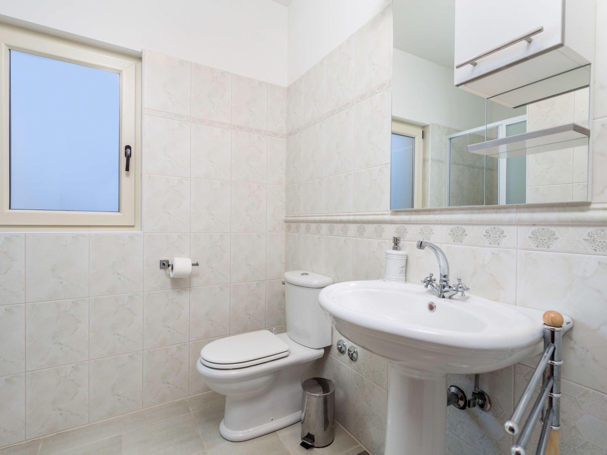 A bathroom with a toilet, sink, and mirror.