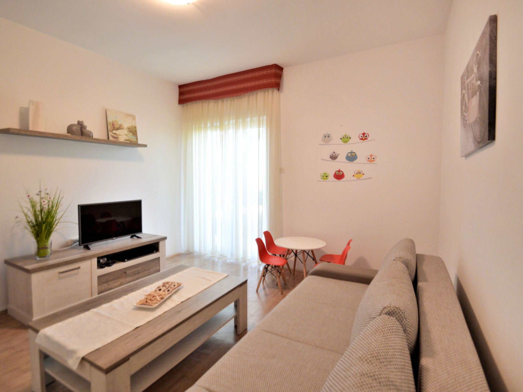 A living room with a sofa, a TV, a coffee table, and a dining area with chairs.