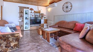 Un salon avec un plafond en bois, une grande horloge, un téléviseur et un canapé.