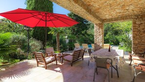 An outdoor patio with stone columns, a red umbrella, and outdoor furniture. - Villa Crispo by Interhome (Medulin)